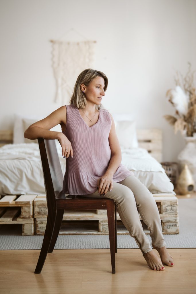 Žena s blond vlasy na hnědé židli při portrétním focení.