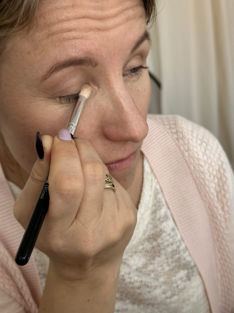 Žena si štětečkem nanáší oční stíny na kurzu líčení