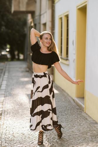 Blond dívka při portrétním focení před domem dívající se bokem