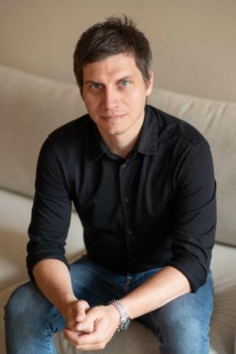 Muž v černé košili při business focení sedící na gauči