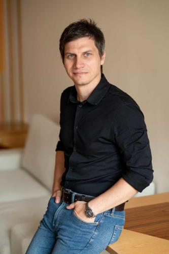 Muž v černé košili při business focení před béžovým pozadím