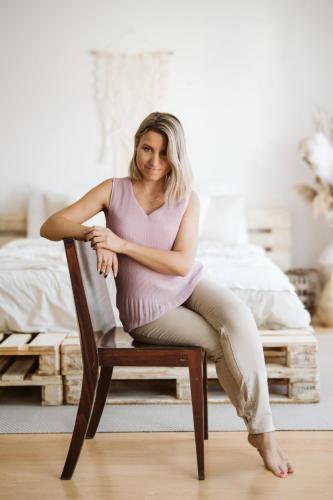 Žena s blond vlasy na hnědé židli při portrétním focení v ateliéru