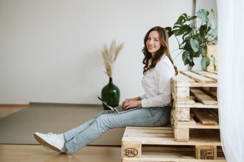 Profesní portrét ženy s dlouhými hnědými vlasy sedící na paletách